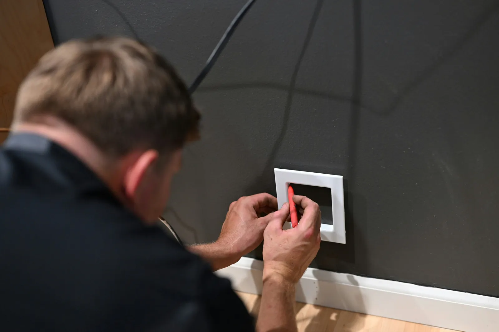 a man fixing a light switch on a wall